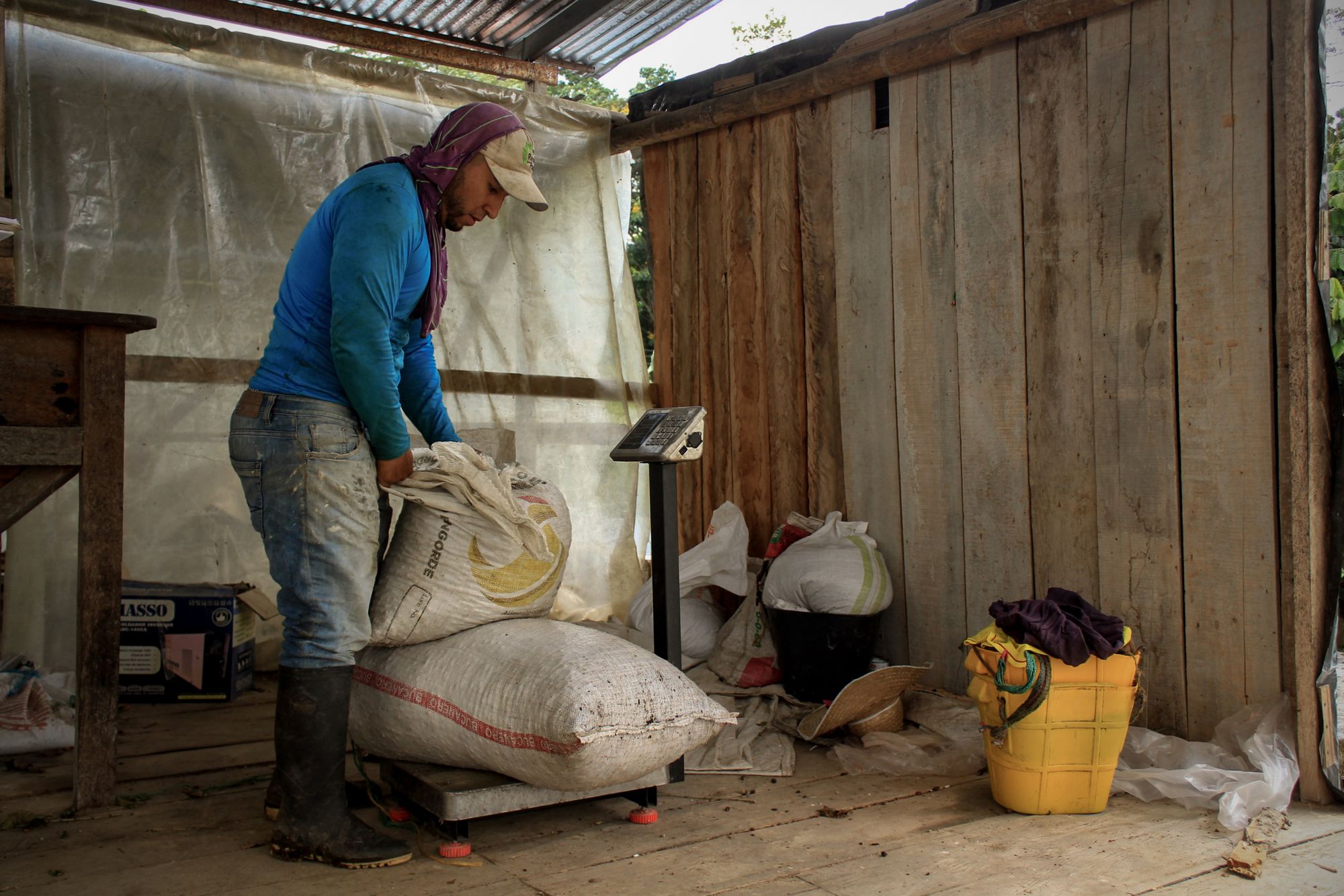 A farmer weighing filled sacks of produce on a scale inside a farm store